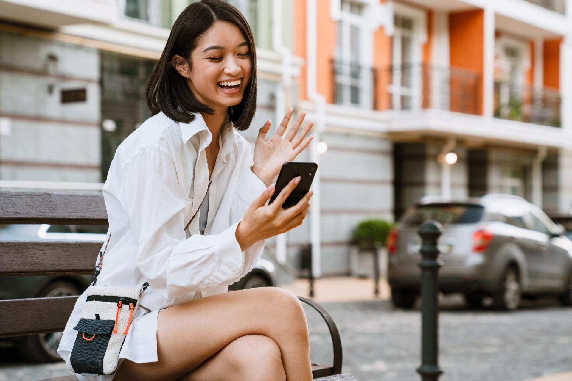 A young woman excitedly manages her second chance checking account from her smartphone.